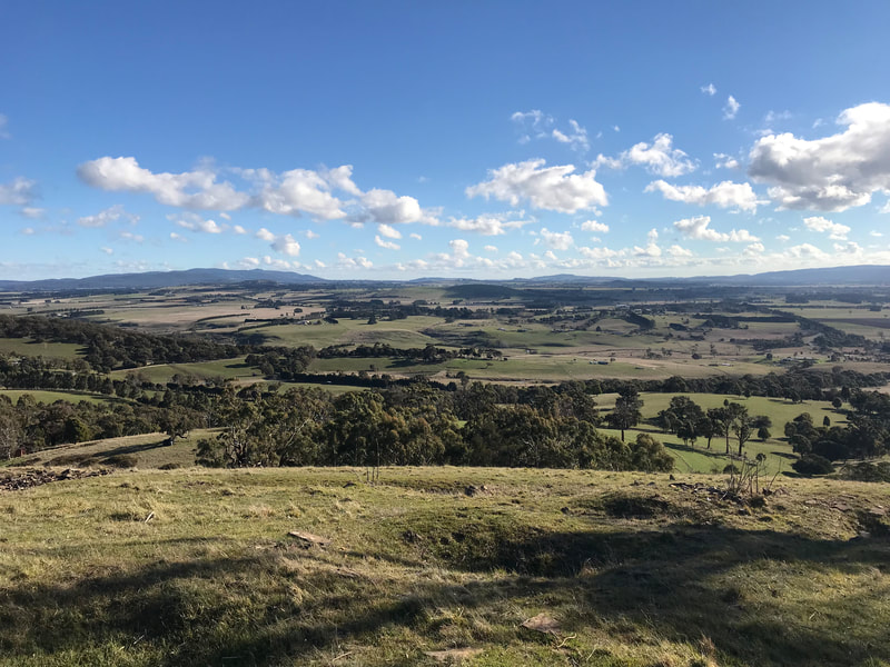 View from the top of Northern Hope looking out towards Lancefield and the Macedon Ranges. Blue skies and rolling green hills